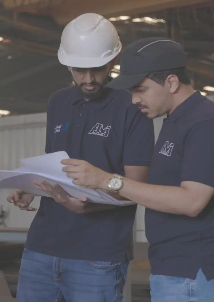 AMI workers reviewing engineering plans at the factory